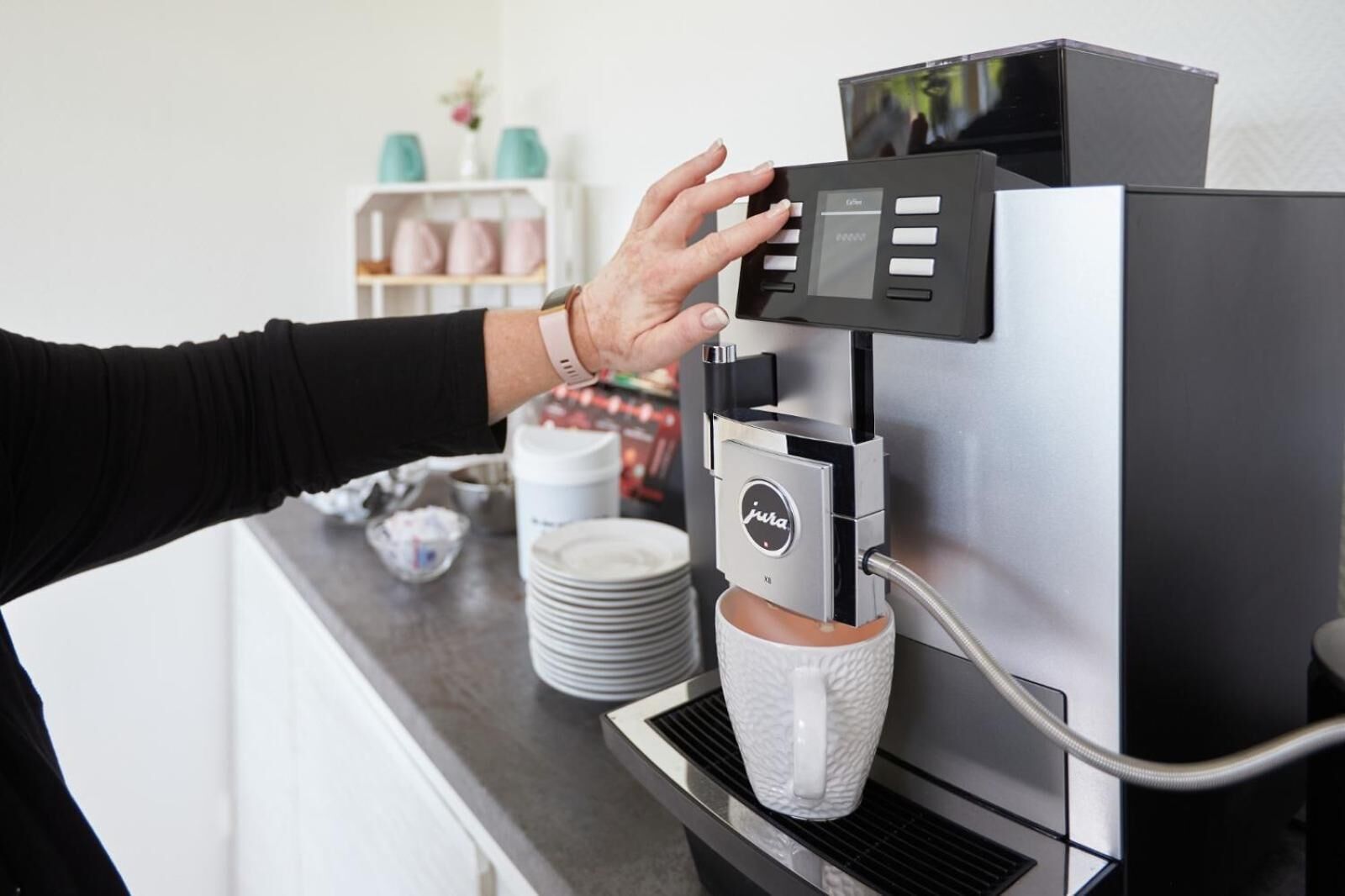 Una persona operando una máquina de café con panel de control y espumador de leche.