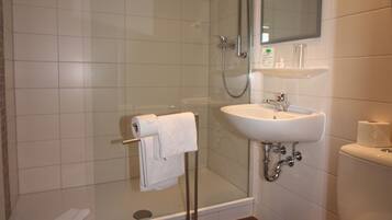 A bathroom with a shower, sink, toilet, and a glass-enclosed shower stall.