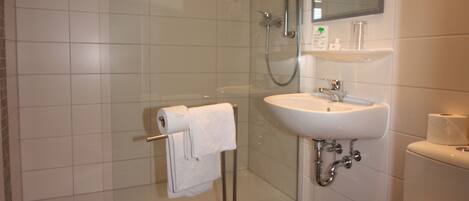 Un baño con ducha, lavabo, inodoro y cabina de ducha con paredes de vidrio.