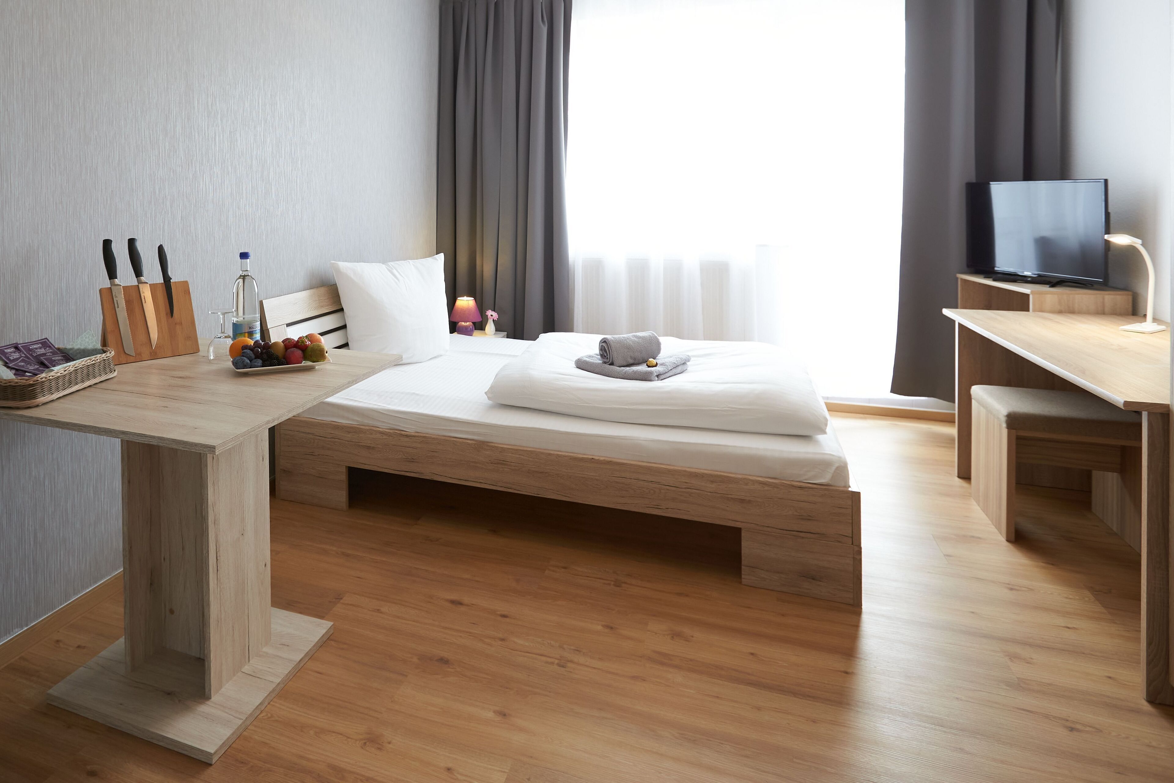 Una habitación de hotel moderna con una cama de madera, un escritorio y un televisor.