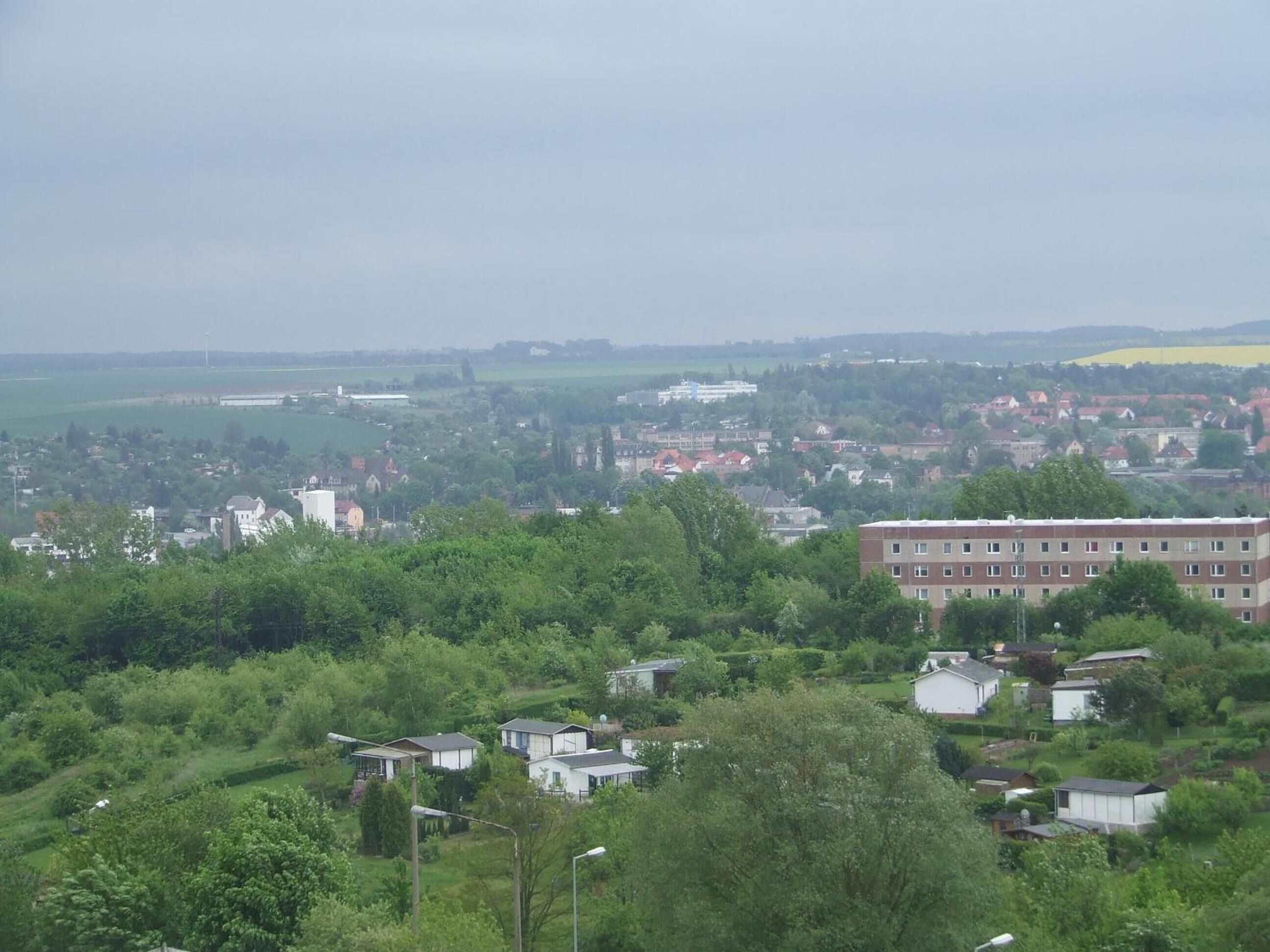Un quartier résidentiel composé de maisons et d’un grand immeuble, le tout entouré de verdure.