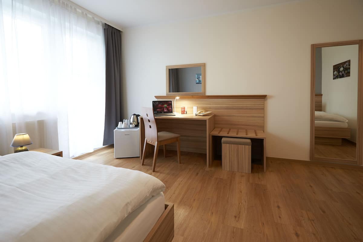 Una habitación de hotel con cama, escritorio, silla y una mesita.