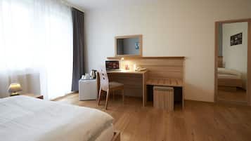 Une chambre d’hôtel avec un lit, un bureau, une chaise et une petite table.