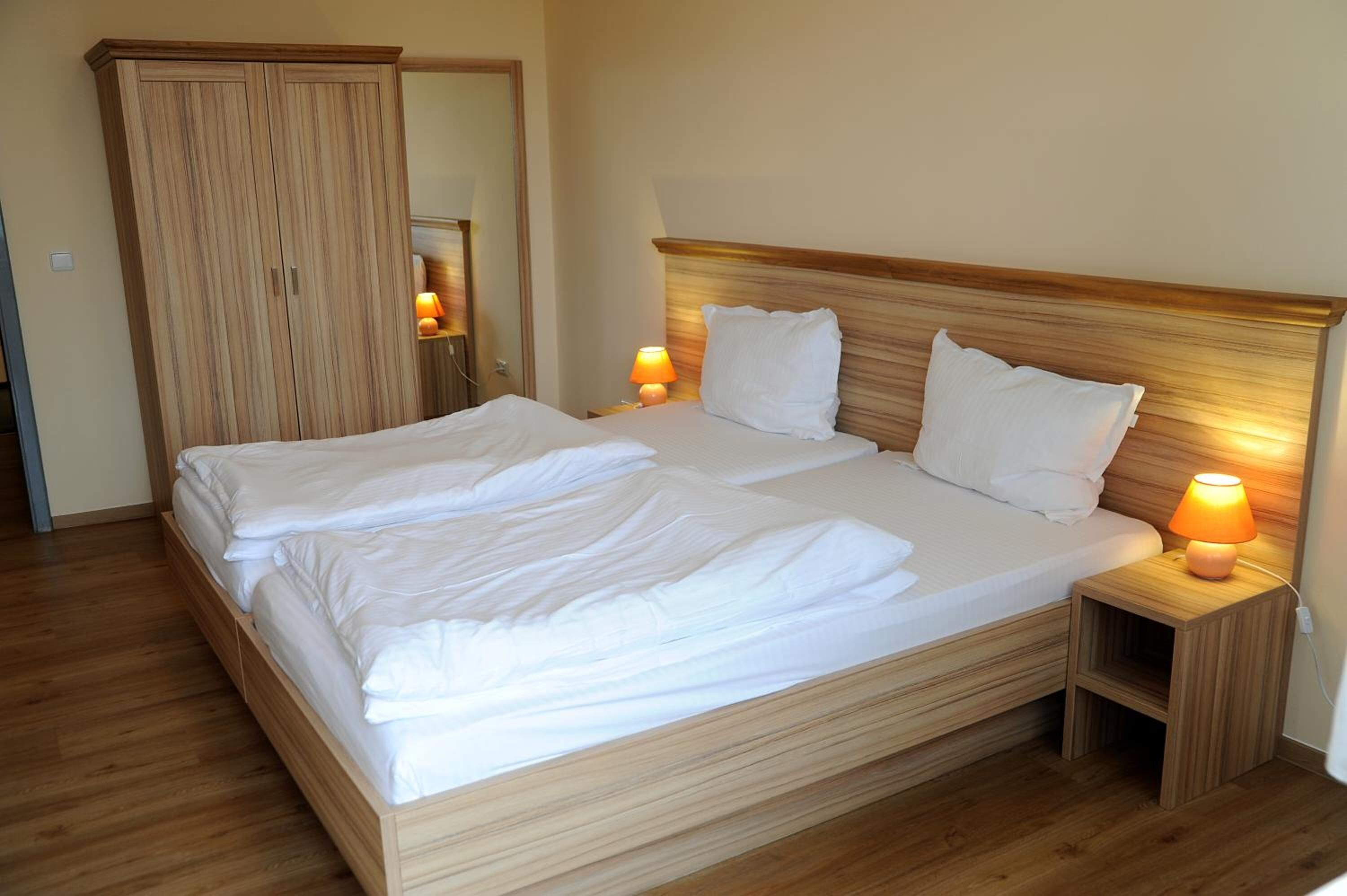 Ein ordentlich bezogenes Bett mit weißen Leinen, einem Holzkopfende und zwei Nachttischlampen.