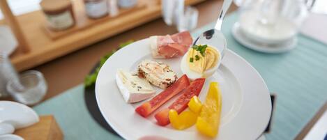 Une assiette contenant divers aliments, notamment de la viande, des œufs et des fruits, et une main tenant une cuillère.
