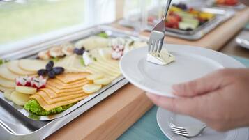 Una mesa de buffet con distintos alimentos como queso, frutas y verduras.