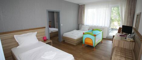 Una habitación de hotel con dos camas, un escritorio con computadora y una ventana con cortinas.