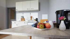 A kitchen with white cabinets, a wooden countertop, and a fruit plate. - Hotel Weimarer Berg (Apolda)