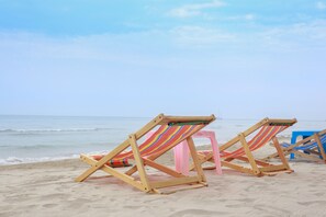 Beach chairs and a pink stool on a sandy beach with the ocean in the background. - Sang Aroon Bungalow (Ko Chang)