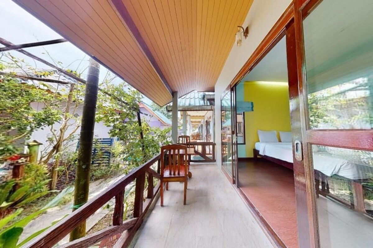A balcony with wooden railings, a table with chairs, and a view of greenery.