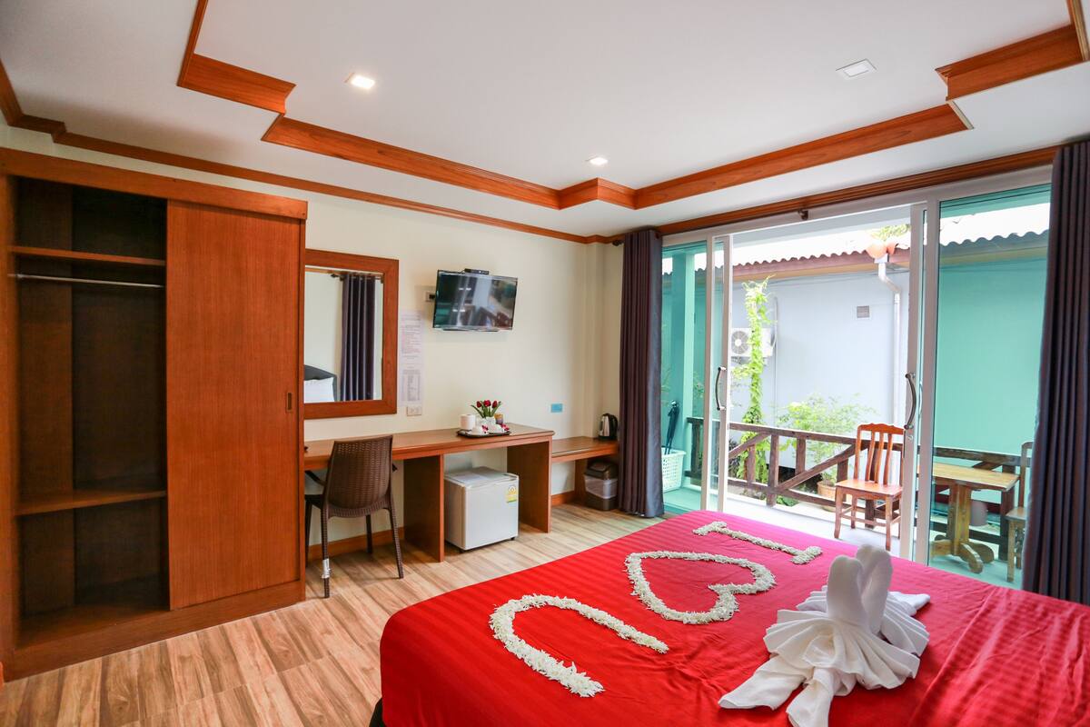 Ein Hotelzimmer mit Bett, Schreibtisch, Stuhl, Fernseher und einem Balkon mit Tisch und Stühlen.