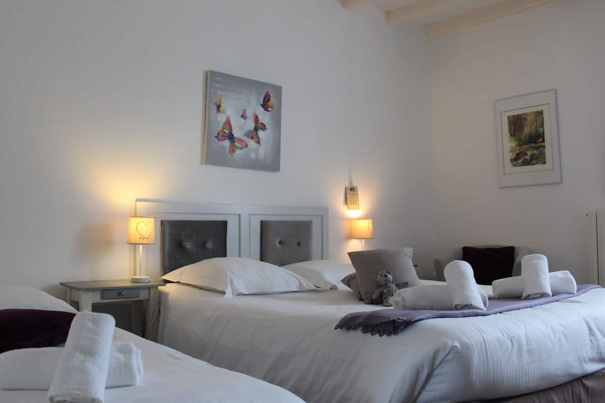 Una habitación de hotel con dos camas, cabeceros, lámparas de noche y obras de arte en las paredes.