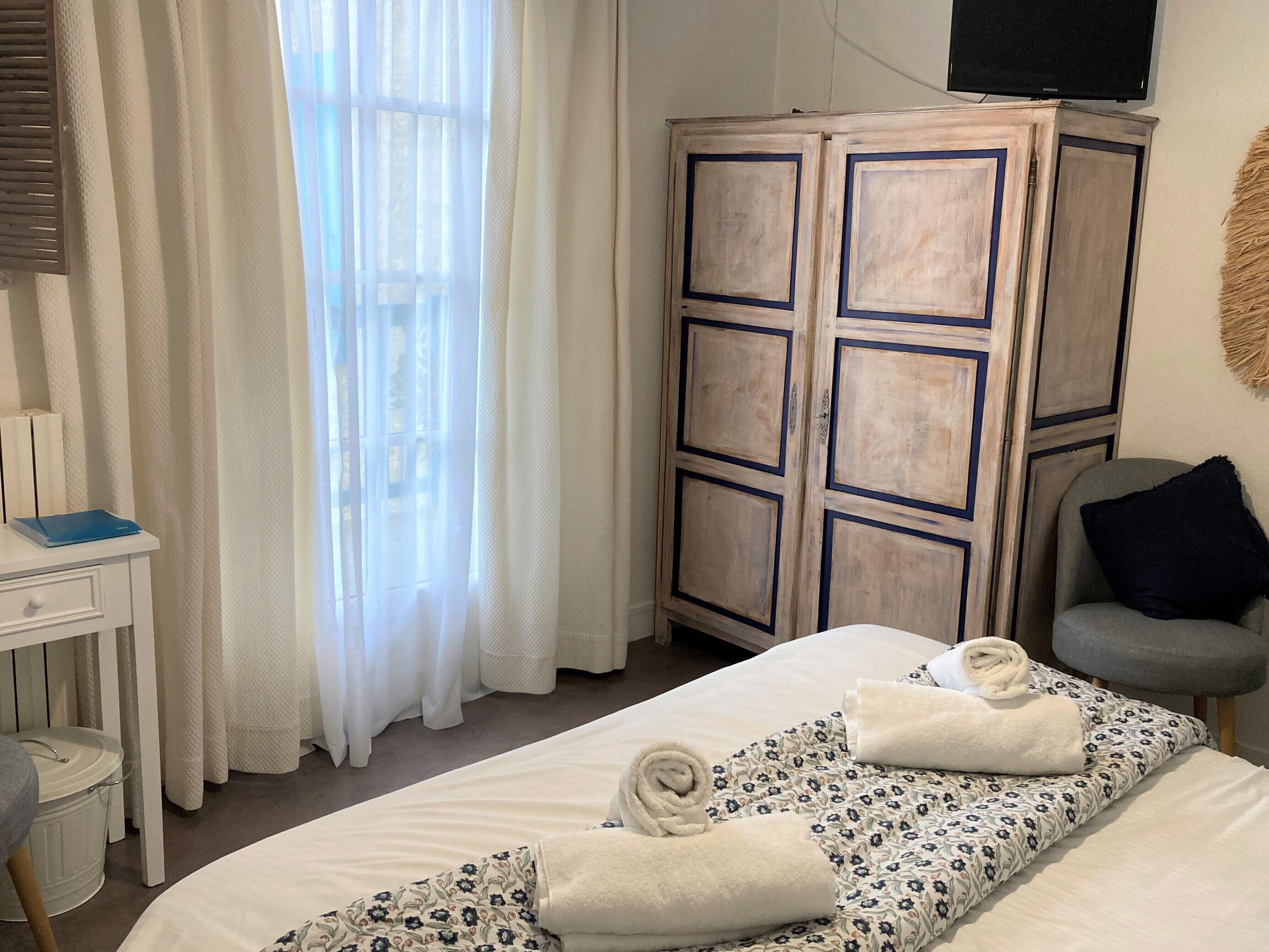 Una camera d'albergo con un letto, una scrivania, un armadio e una sedia.