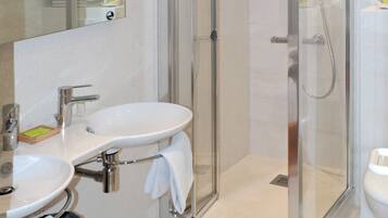 Een moderne badkamer met een douchecabine van glas, een wastafel en een toilet.