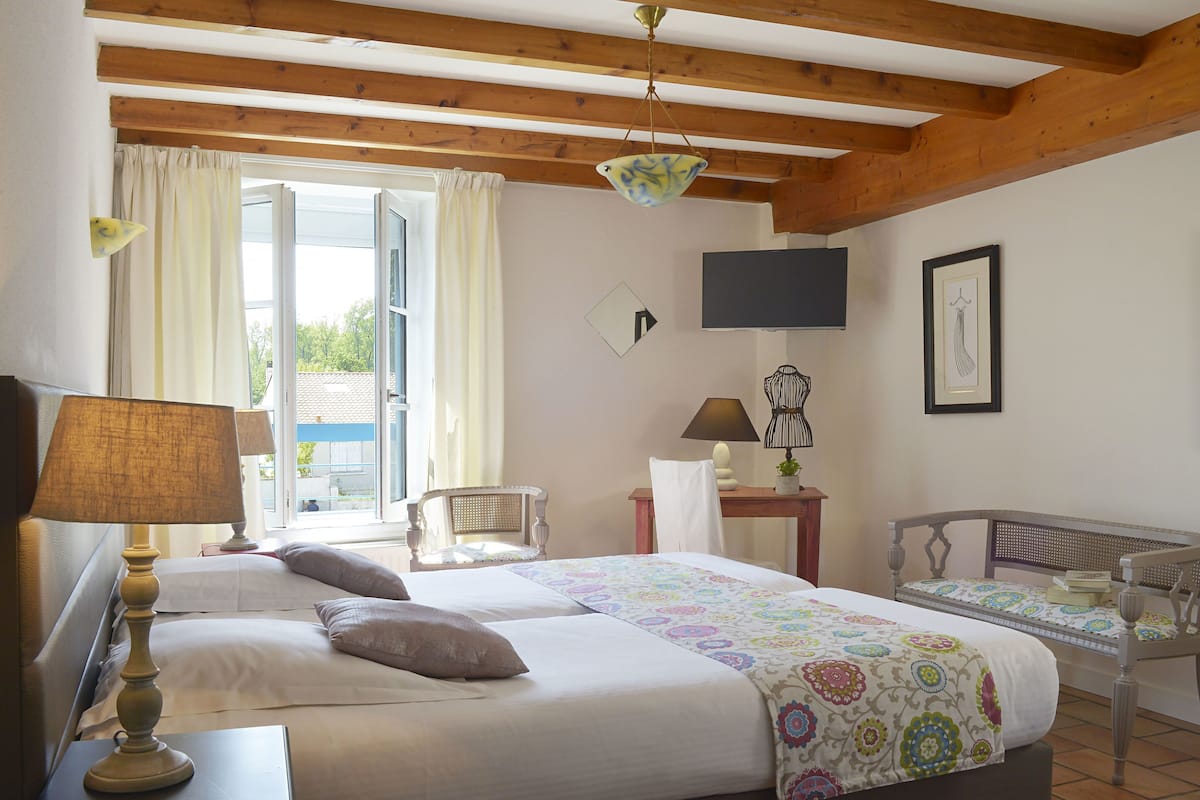 Habitación de hotel con dos camas, televisión, una silla y un escritorio.