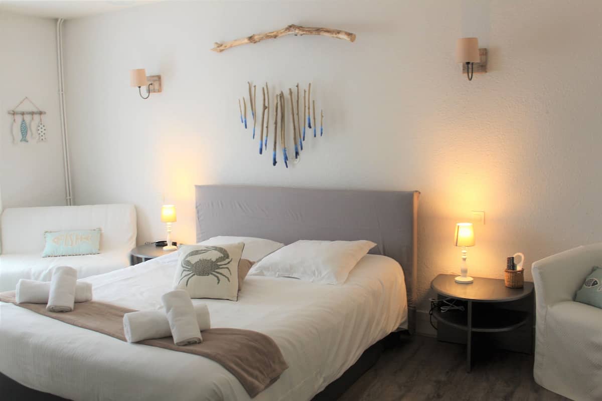 Habitación de hotel con una cama, dos mesitas de noche, una silla y decoración en la pared.