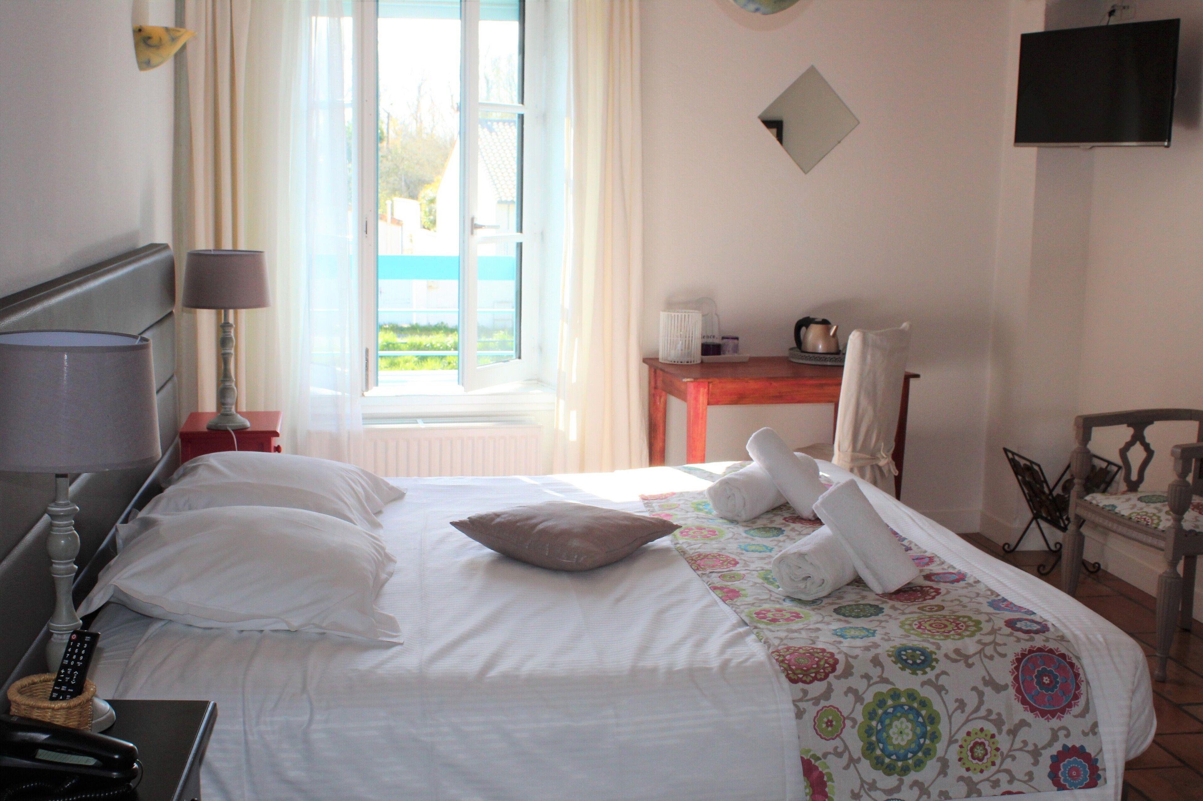 Una habitación de hotel con cama, escritorio, silla, lámpara y televisor.