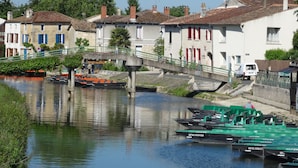 Un canal con barcos, un puente y edificios con contraventanas rojas.