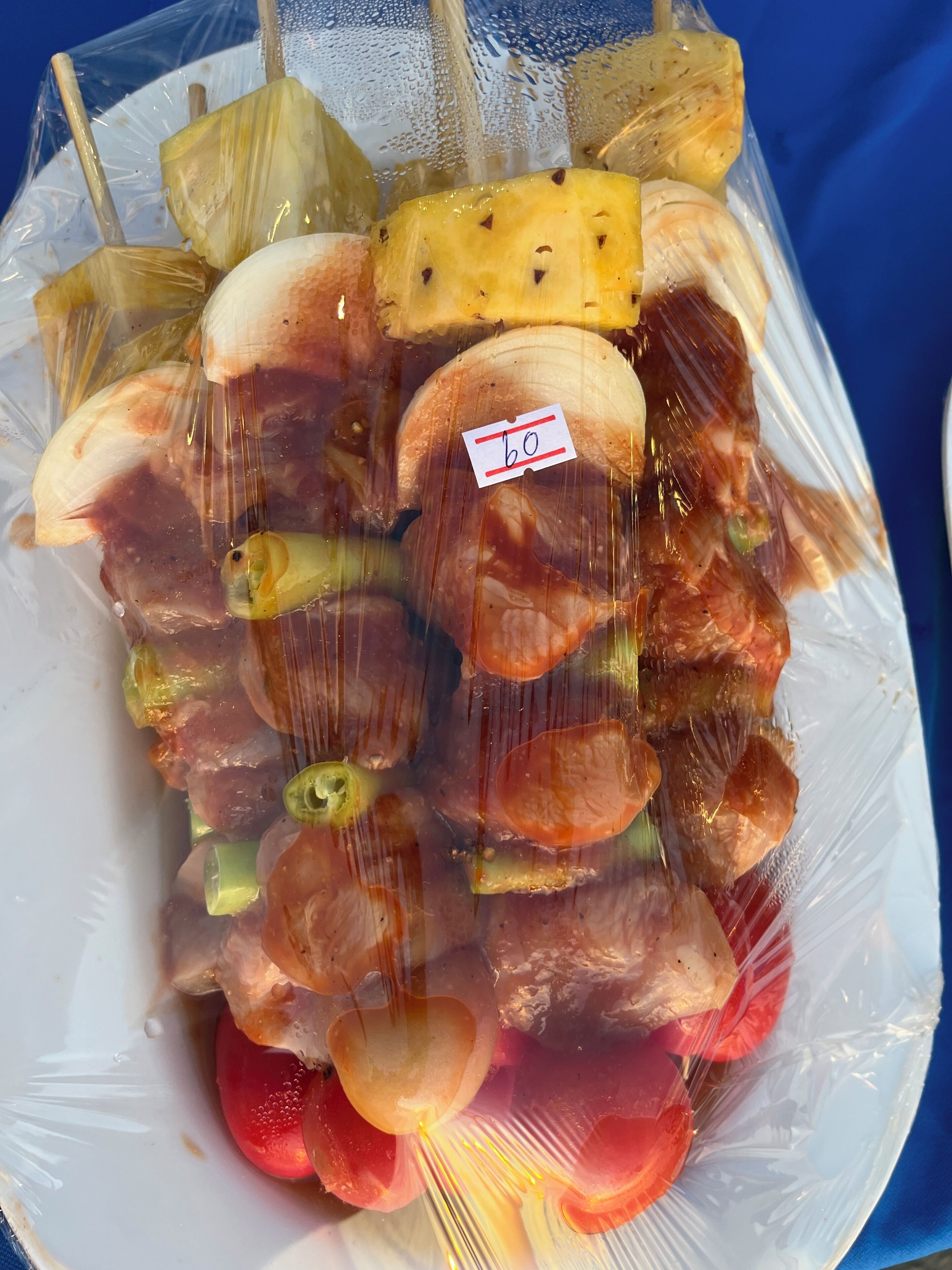 A plastic bag containing various fruits, including pineapple, kiwi, and tomatoes, with a price tag visible.