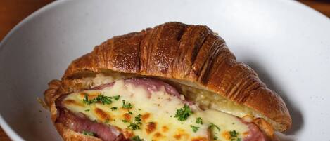 A croissant sandwich with cheese and ham on a white plate.