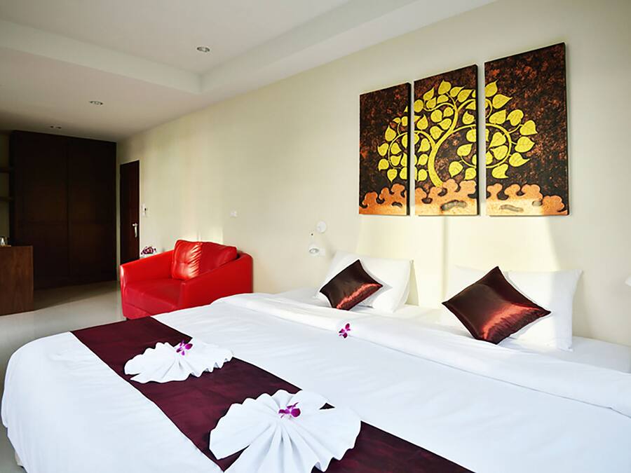 Una habitación de hotel con una cama grande, un sillón rojo y un cuadro en la pared.