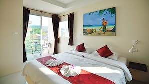 A hotel room with a bed, a painting of a beach scene, a balcony with a table and chairs, and a view of the outdoors. - At Kamala Hotel (Kamala)
