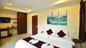 A hotel room with a large bed, a flat-screen TV, a wooden desk, and a door. - At Kamala Hotel (Kamala)