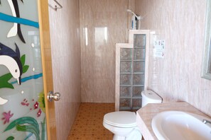 Un baño con inodoro, lavamanos y zona de ducha.