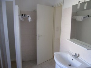 A bathroom with a white sink, a mirror, and a shower area. - Résidence Anna (Centuri)