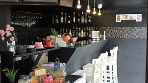 A bar area with a black counter, white chairs, and various bottles and glasses. - SP Place Hotel (Ko Chang)