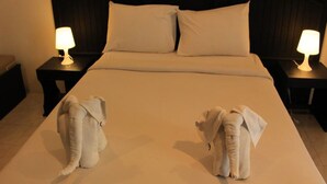 A hotel room with a large bed, two nightstands with lamps, and two elephant-shaped pillows. - SP Place Hotel (Ko Chang)