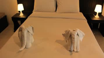 A hotel room with a large bed, two nightstands with lamps, and two elephant-shaped pillows.