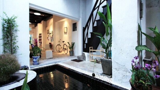 A modern indoor pool area with a black tiled floor, surrounded by potted plants and a staircase. - The Rommanee Boutique Guesthouse (Phuket)