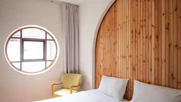 Quarto com cama, janela redonda, cadeira e parede de painéis de madeira.