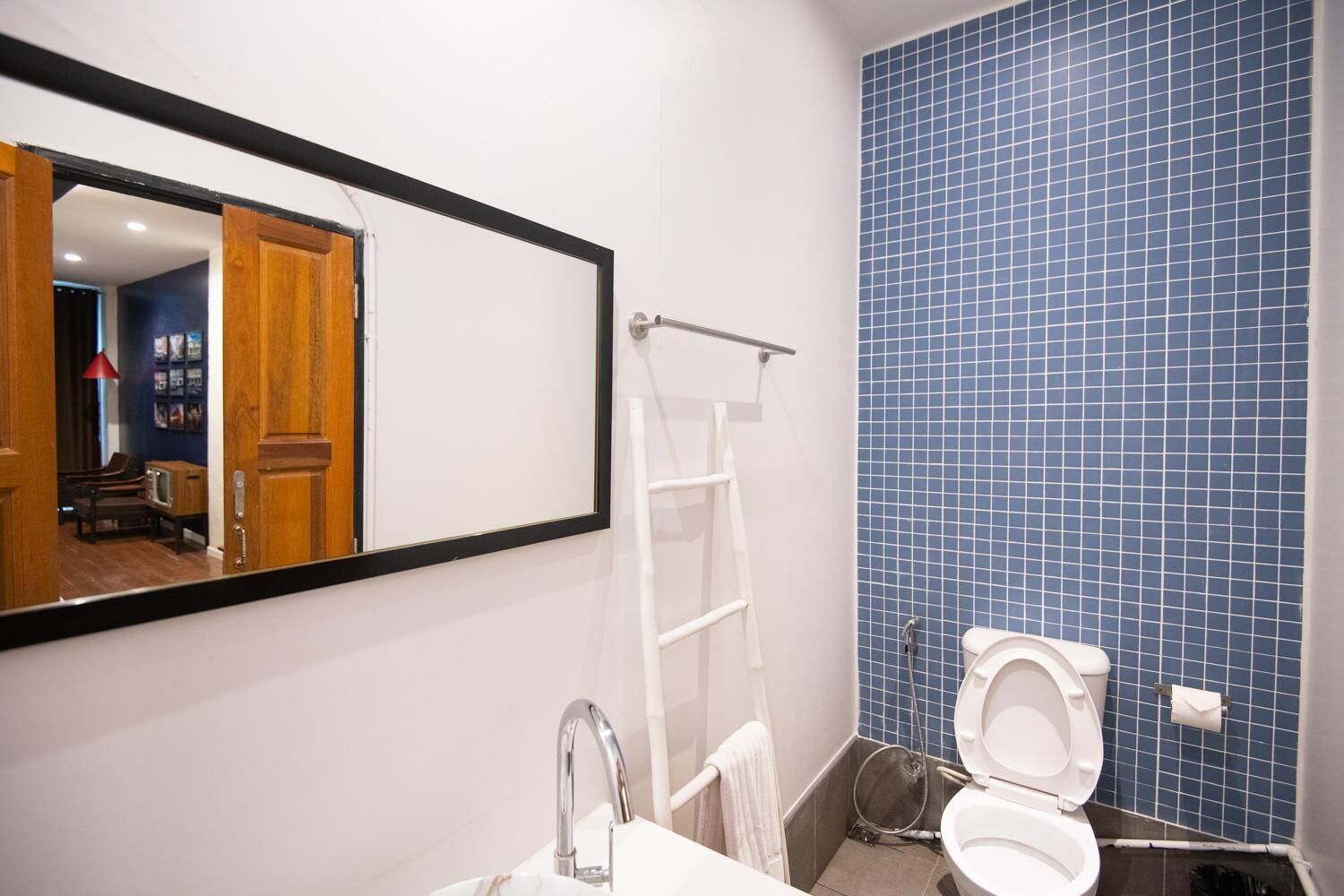Une salle de bain avec un lavabo blanc, un miroir, des toilettes blanches et un mur de douche recouvert de carreaux bleus.