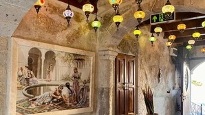 A room with a large painting, a wooden door, and a large vase. - Century Cave Hotel (Nevsehir)
