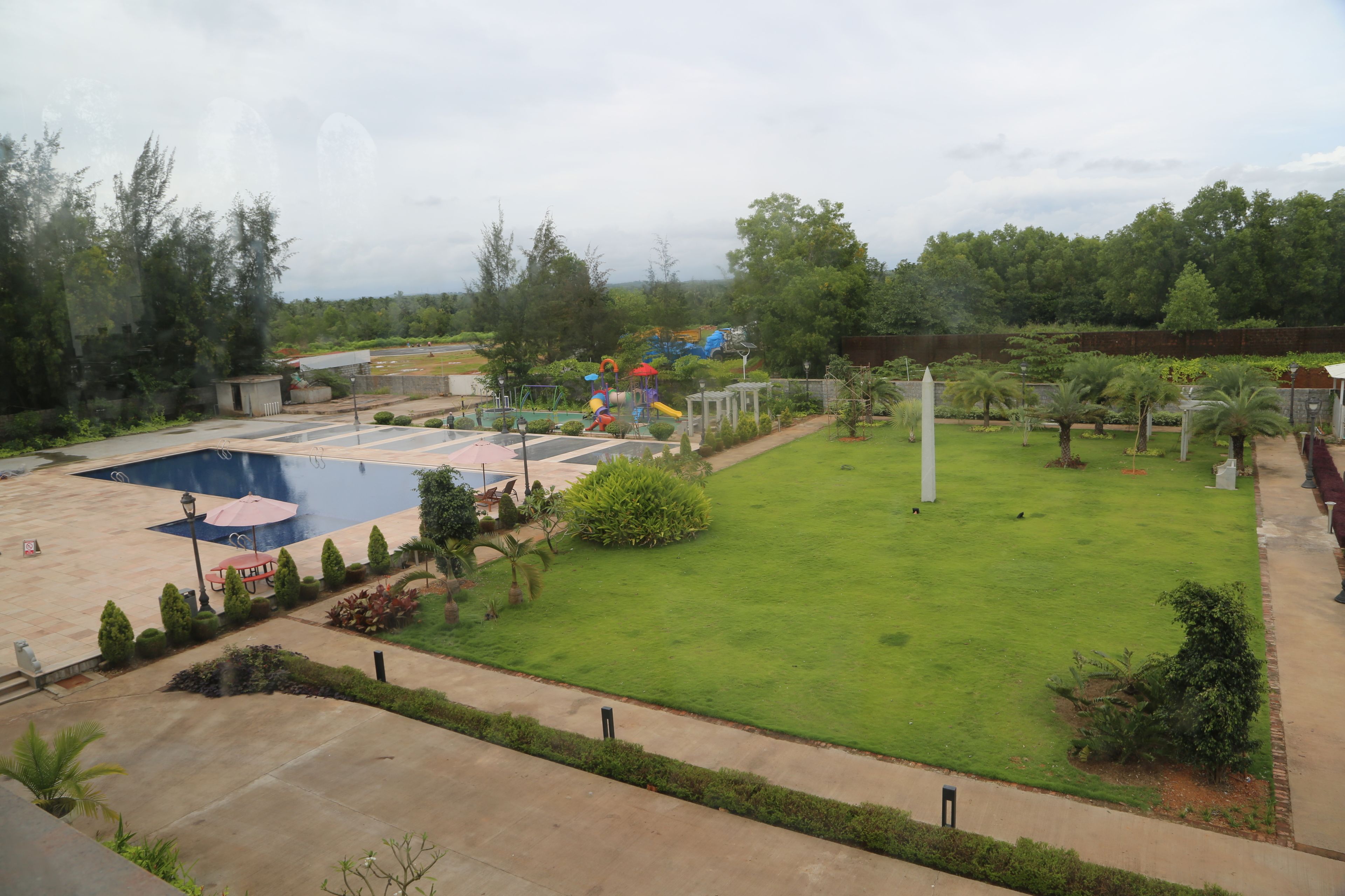 A well-maintained garden with a swimming pool, a playground, and a lawn area.