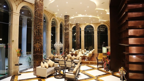 A spacious lobby with marble columns, a chandelier, and a seating area with sofas and chairs. - UVA Meridian bay resort and spa (Kundapur)