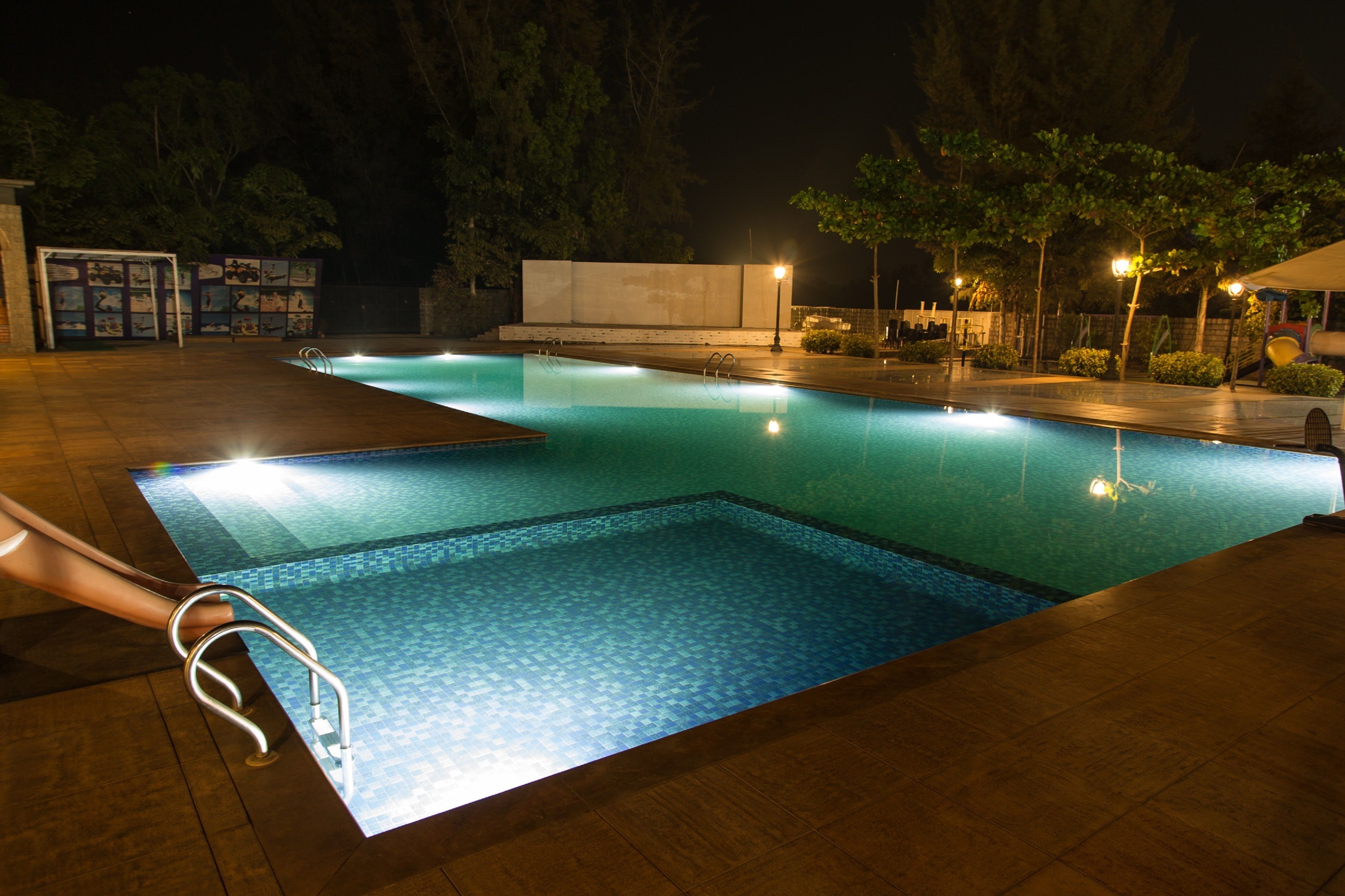 Una piscina con plataforma de cerámica y escalera de metal.