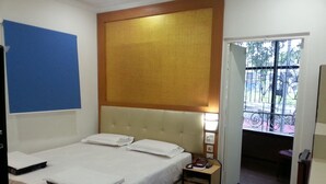 Una habitación de hotel con cama, mesita de noche y vistas al exterior.
