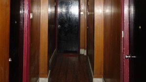 Un pasillo con paredes de madera y una puerta oscura al final.