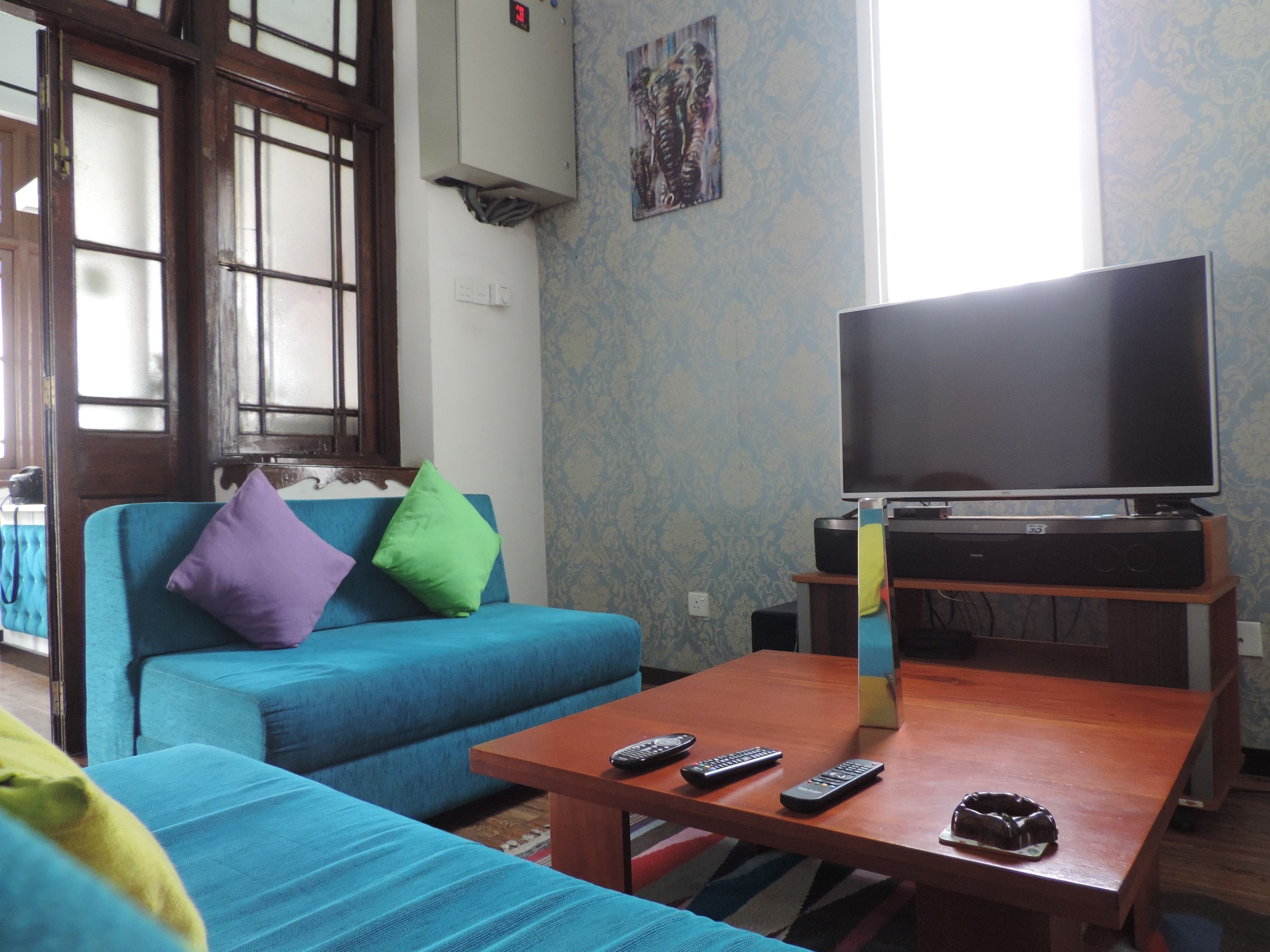 A living room with a blue sofa, a wooden coffee table, and a flat-screen TV on a stand.