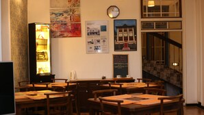 A dining area with wooden tables and chairs, a clock, and a menu board. - VILLA 92 - City Hotel - Hostel (Kandy)
