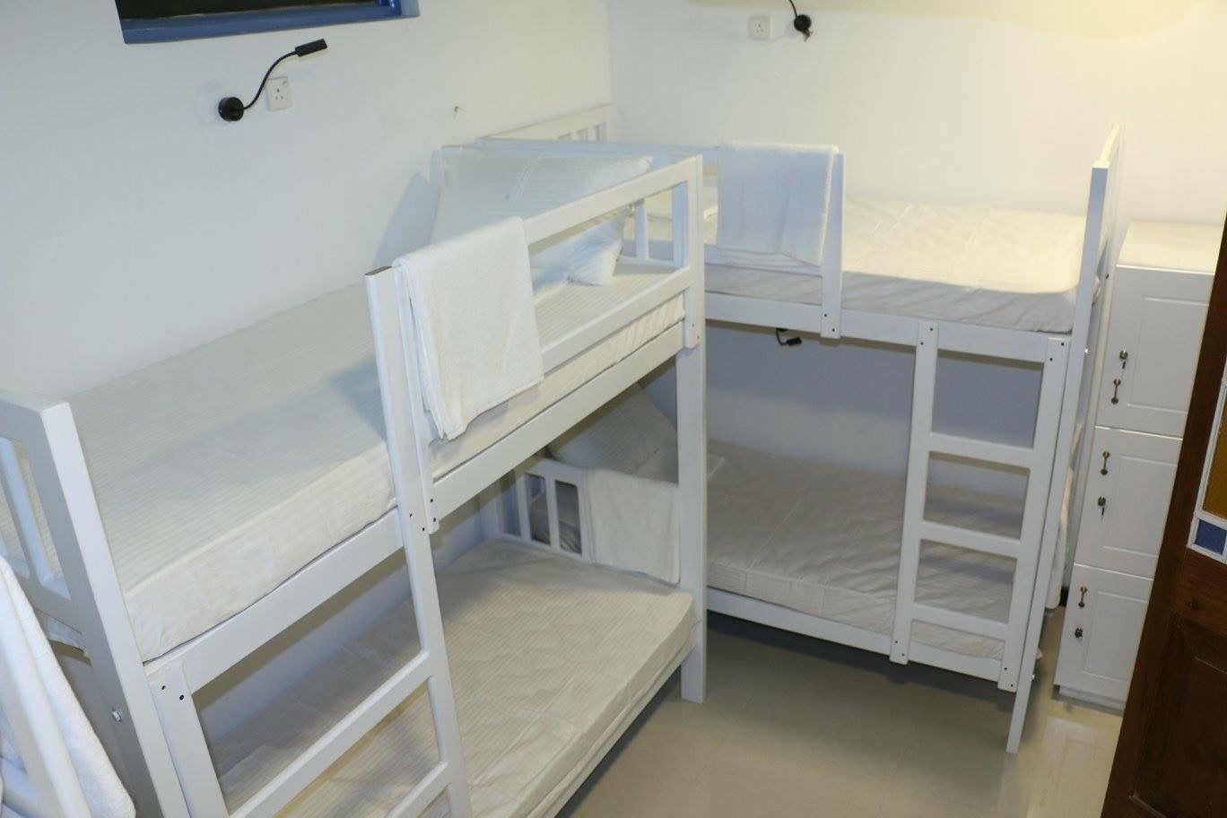 Une chambre avec un lit superposé, du linge de lit blanc et une petite fenêtre.