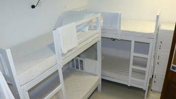 Une chambre avec un lit superposé, du linge de lit blanc et une petite fenêtre.