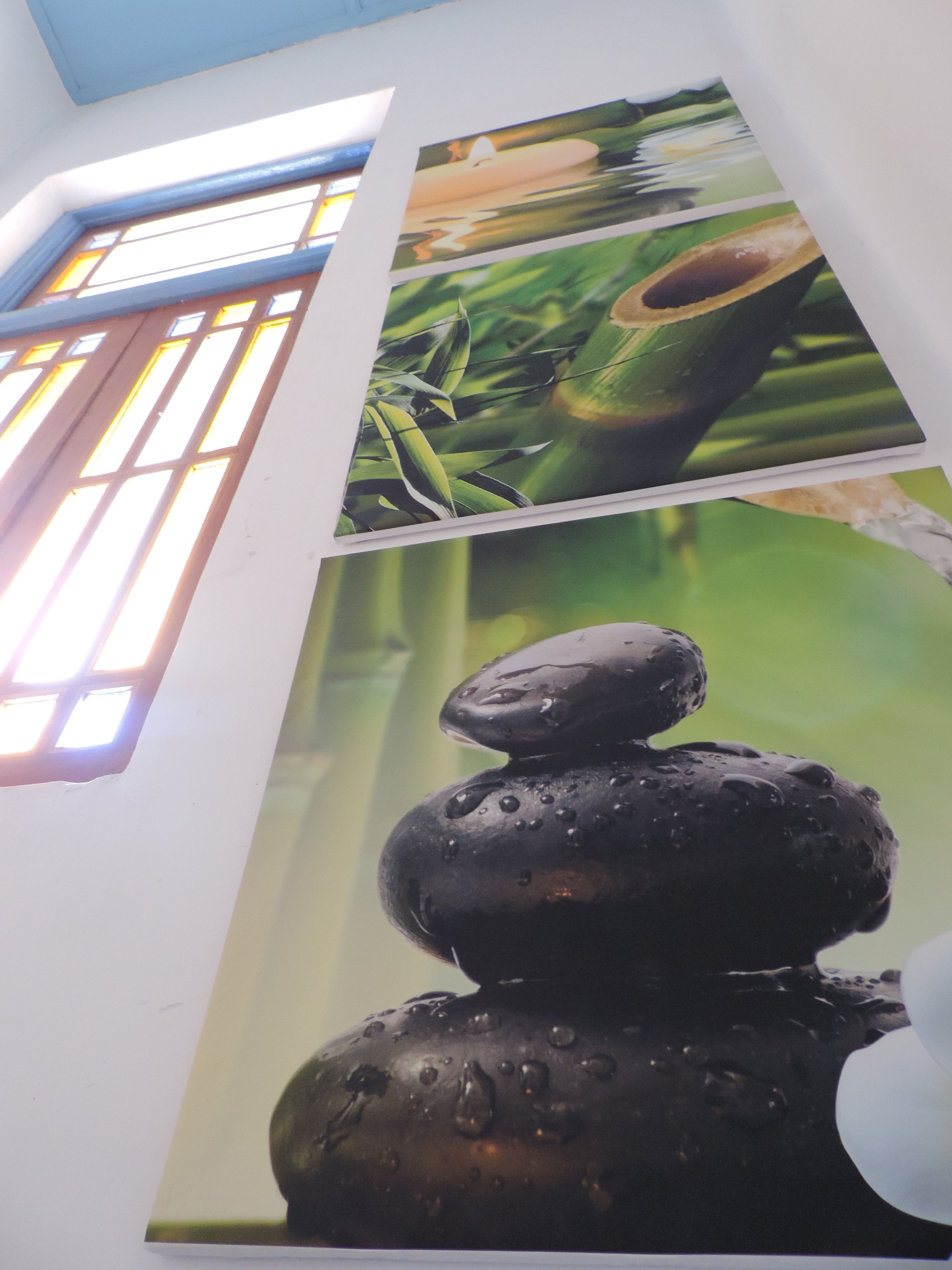 A wall with a large framed picture of a bamboo shoot and a stack of stones.
