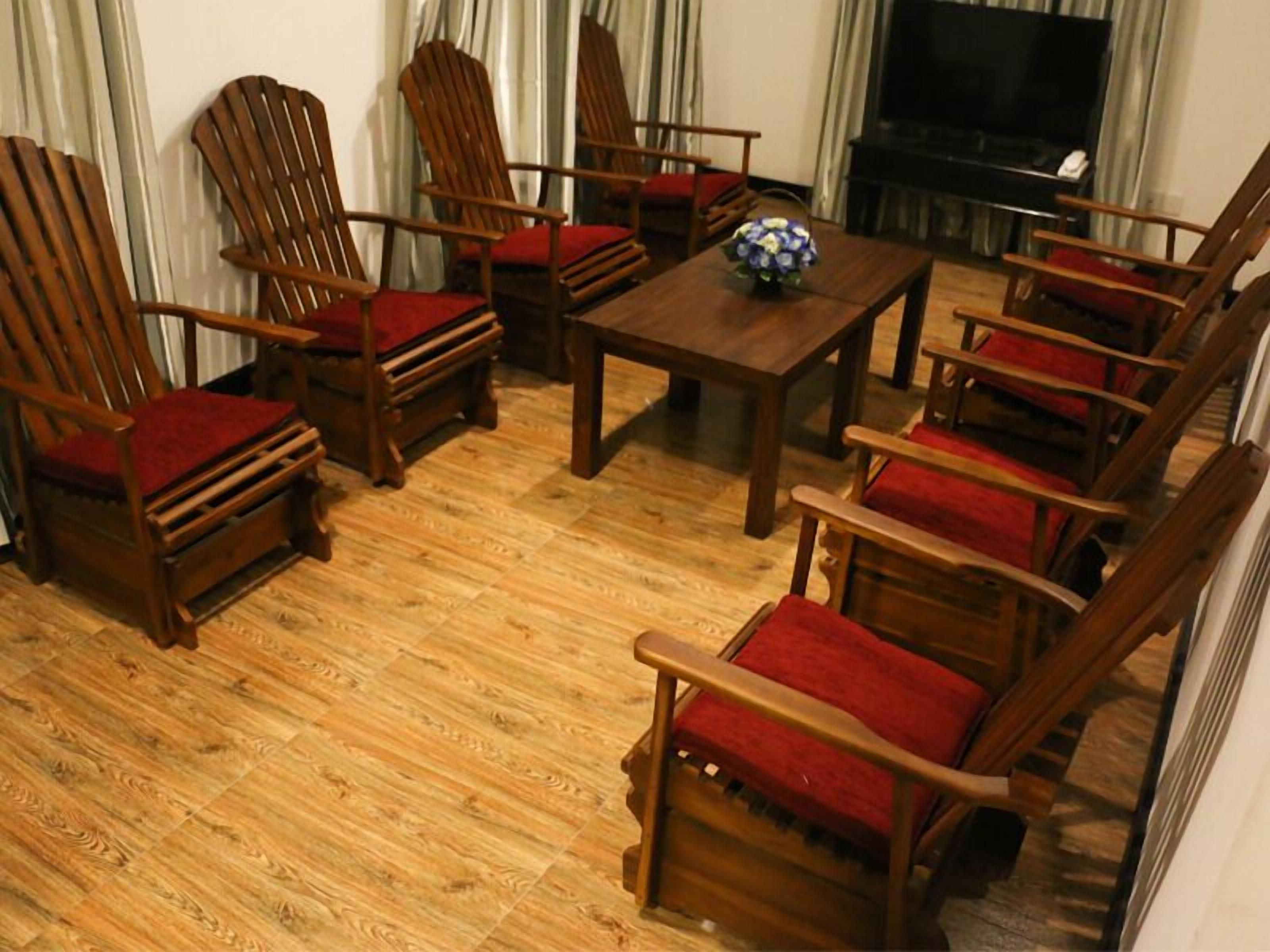 Un salon meublé de meubles en bois, notamment des chaises et une table, et équipé d’un téléviseur.