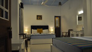 A hotel room with two beds, a desk, a chair, a mirror, and a ceiling fan. - VILLA 92 - City Hotel - Hostel (Kandy)