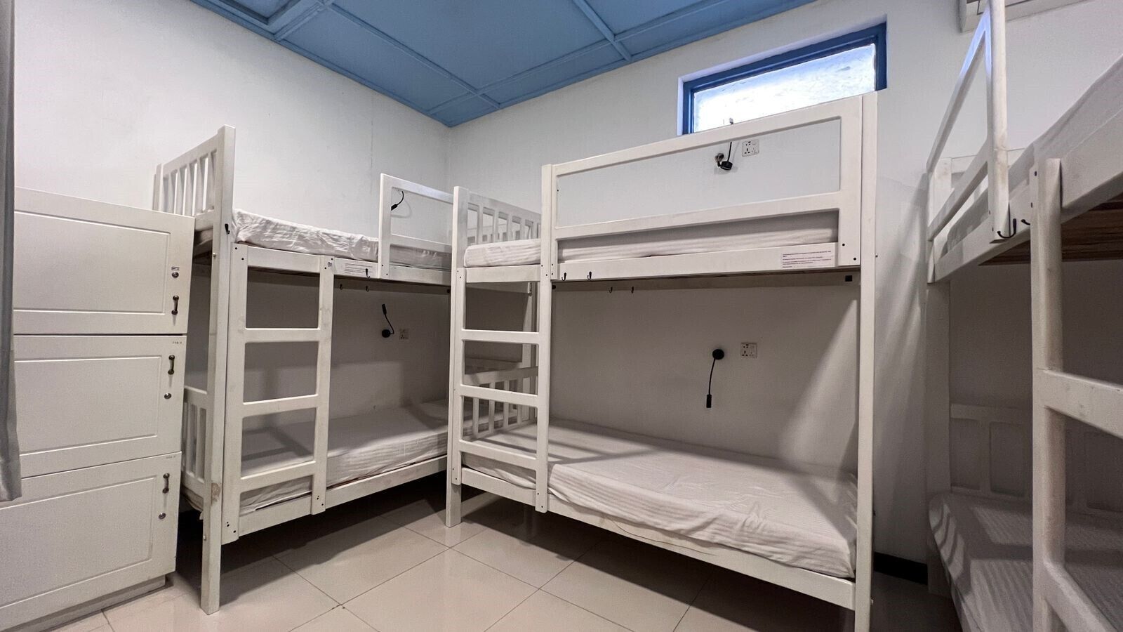 A room with bunk beds, a window with a view, and a door with a handle.