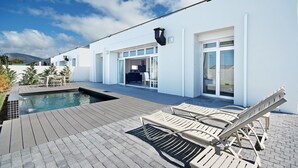 A modern house with a swimming pool, outdoor seating, and a large glass door leading to a patio. - Spatalla Holiday Homes (Kleinmond)